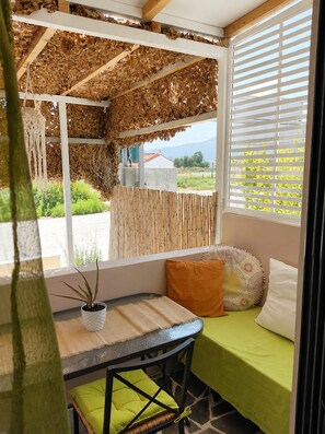 Ein gemütliches Zimmer mit Fenster, einem Tisch mit Pflanze und einem grünen Bett.