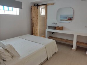 Ein Schlafzimmer mit einem Bett, einer Holztür, einem weißen Nachttisch und einem Wandspiegel.