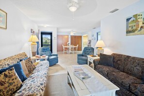 Ein Wohnzimmer mit einer Couch, Sesseln, einem Couchtisch und einem Essbereich mit Tisch und Stühlen.