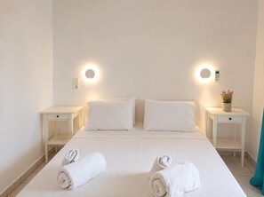 Ein Hotelzimmer mit einem Bett, zwei Nachttischen, einer Wandbedienung und einer Zimmerpflanze.