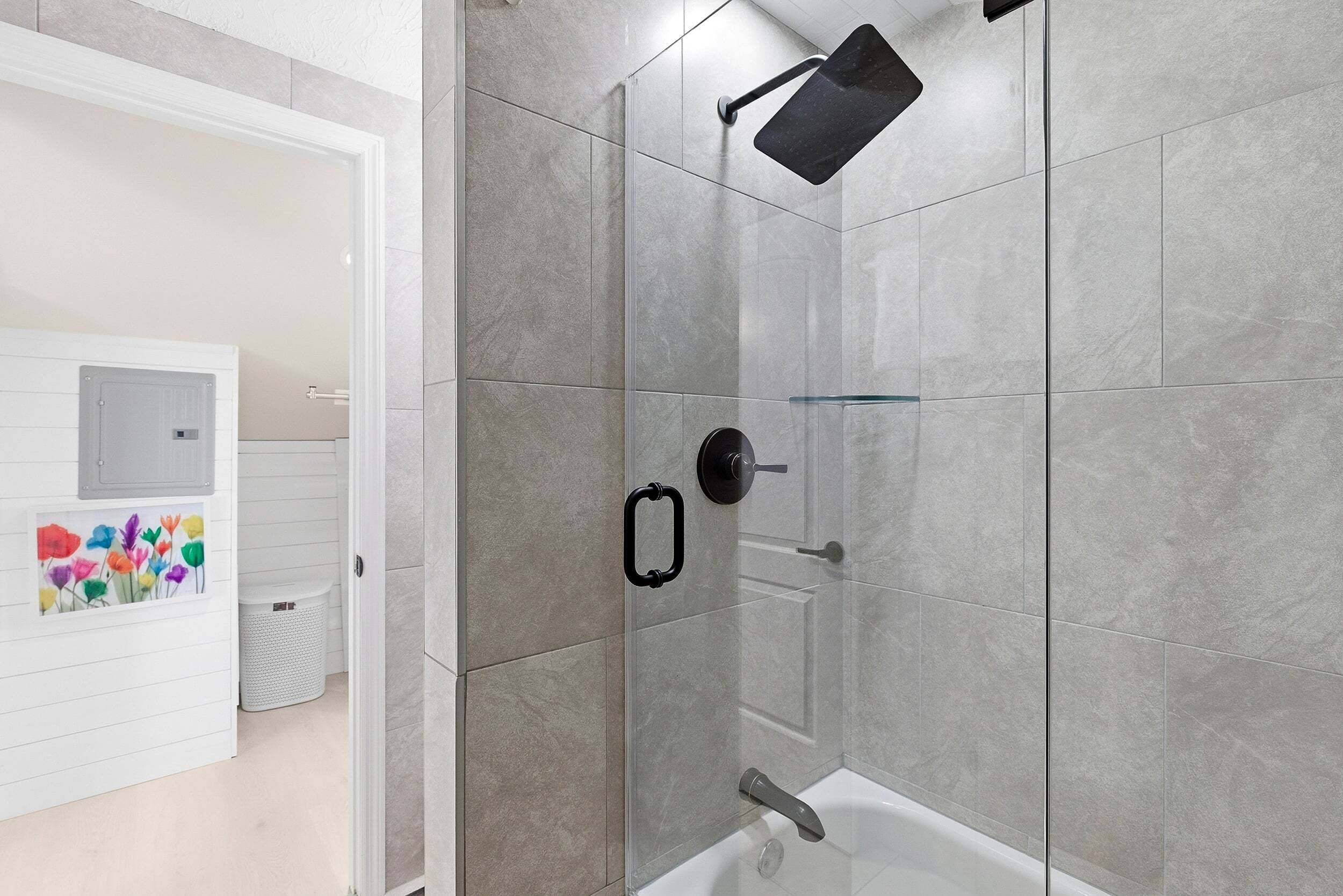 Een moderne badkamer met een douchecabine van glas, een witte badkuip en een handdoekhouder.