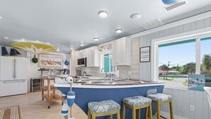 A modern kitchen with a central island, bar stools, and a view of the outside. - La De Dah (Edgewater)