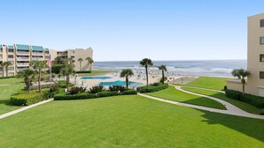 A hotel with a pool, palm trees, and a view of the ocean. - Updated Oceanview Retreat With Pools, Pickleball & Direct Beach Access (New Smyrna Beach)