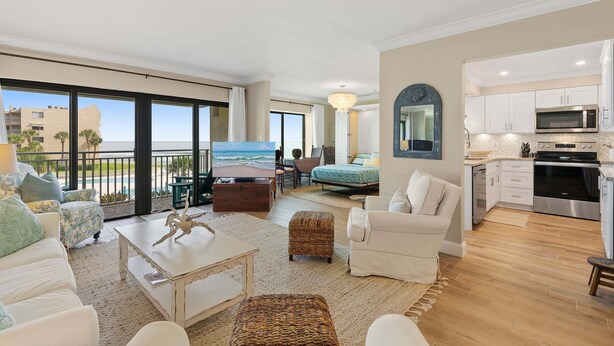 A spacious living area with a balcony, a kitchen, and a dining area. - Updated Oceanview Retreat With Pools, Pickleball & Direct Beach Access (New Smyrna Beach)