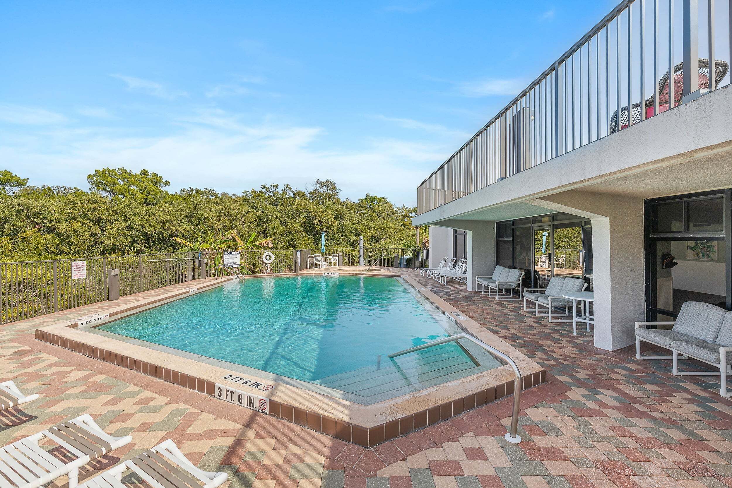 A swimming pool with lounge chairs and a covered patio area.