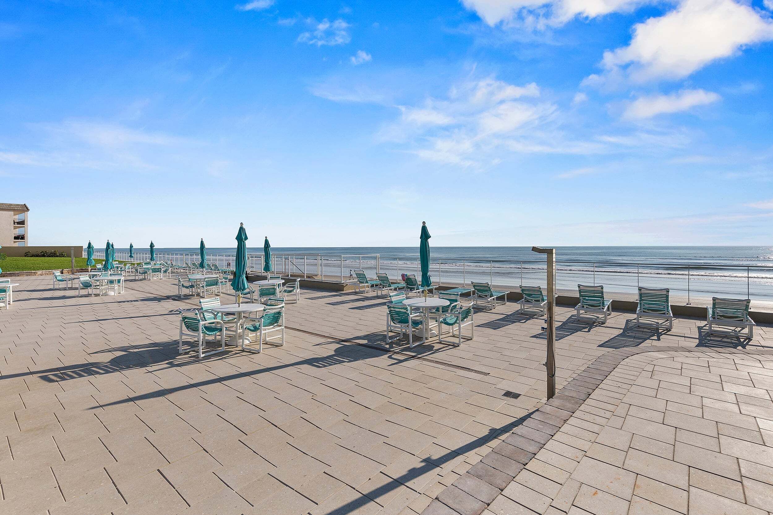 A seaside terrace with outdoor seating and a view of the ocean.