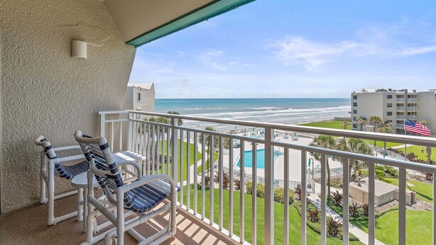 Un balcon avec vue sur la plage, la piscine et les bâtiments de l’hôtel.