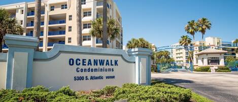 A sign for Oceanwalk Condominiums at 5300 S. Atlantic venue, with a view of the building and palm trees.