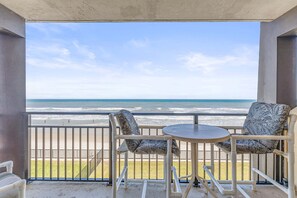 A balcony with a view of the beach, two chairs, and a small table. - Hawaiian Inn 332 (Daytona Beach Shores)