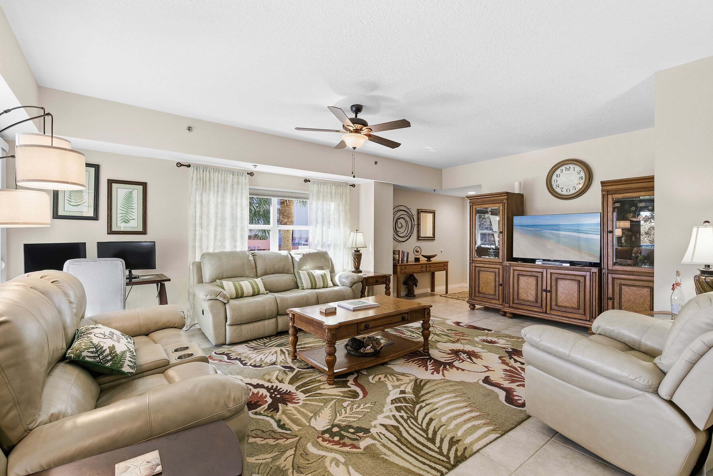 A living room with a sofa, coffee table, TV, and ceiling fan.