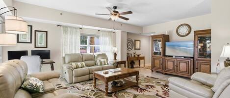 A living room with a sofa, coffee table, TV, and ceiling fan.