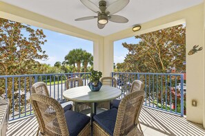 Eine überdachte Terrasse im Freien mit einem runden Tisch, Korbstühlen und einem Deckenventilator.