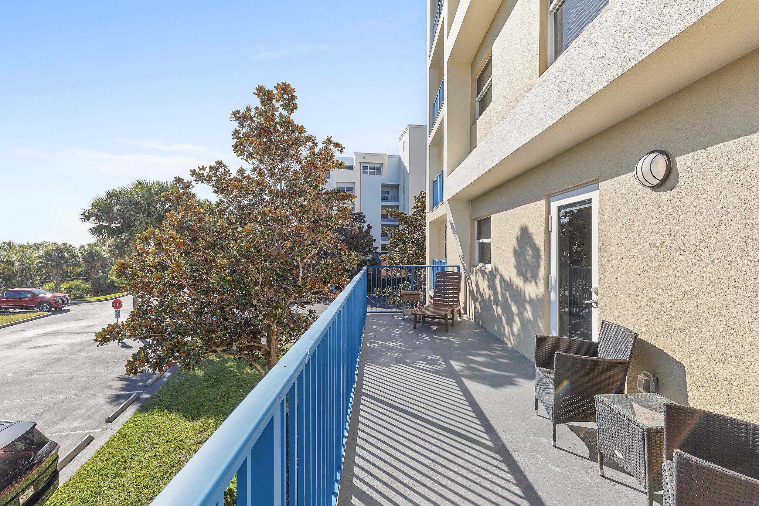 Un balcon avec des meubles en osier, un panneau de signalisation indiquant un arrêt obligatoire et un bâtiment en arrière-plan.
