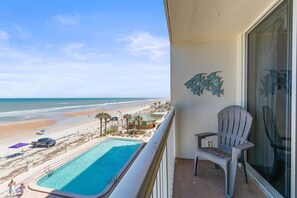 A balcony with a view of a beach, a pool, and a chair. - Daytona Beach Resort 456 (Daytona Beach)