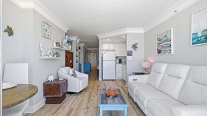 A modern living room with a white sofa, a wooden coffee table, and a dining area with a wooden table and chairs. - Daytona Beach Resort 456 (Daytona Beach)