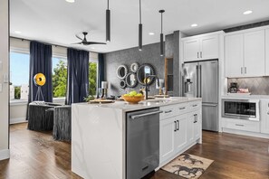 A modern kitchen with a central island, stainless steel appliances, and a view of the outdoors. - Rooftop Oasis - Hot Tub, Nashville City Views (Nashville)