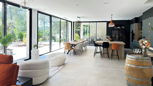 Un intérieur moderne avec de grandes fenêtres, un coin repas et une cuisine.