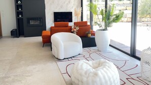 Un salon moderne doté d’une cheminée, de grandes fenêtres et offrant une vue sur l’extérieur.