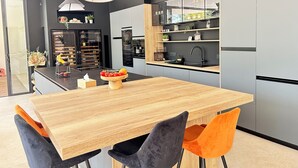 Une cuisine moderne avec une table à manger en bois, deux chaises, un évier noir et un réfrigérateur noir.
