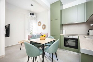 Eine moderne Küche mit grünen Schränken, einem Einbauofen und einer Essecke mit Tisch und Stühlen.