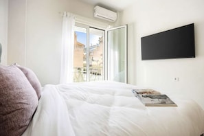 Ein Schlafzimmer mit Bett, einem fensterbelaubten Fenster, einer Klimaanlage und einem flachbildfernseher an der Wand.