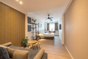 A modern living room with a sofa, a small round table, and a potted plant. - Spacious Studio King Bed & Workspace|Weekend Noise (Athens)