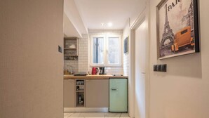 Una cucina compatta con lavastoviglie integrata, una finestra e un poster della Torre Eiffel.