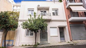 A two-story building with a balcony, a door with a glass panel, and a window. - Modern Studio | King Bed & Work Corner (Athens)