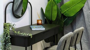 A desk with a mirror, two chairs, a book, a small plant, and a candle. - Modern Studio | King Bed & Work Corner (Athens)