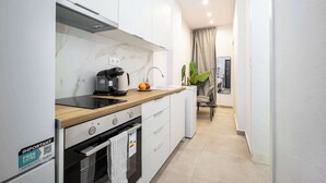 A modern kitchen with white cabinets, a wooden countertop, a coffee maker, and a built-in oven. - Modern Studio | King Bed & Work Corner (Athens)