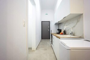 Una cucina piccola con mobili bianchi, uno schienale in marmo e una macchina per il caffè.