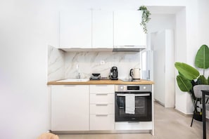 Una cucina moderna con mobili bianchi, un piano di lavoro in marmo, forno integrato e macchina da caffè.