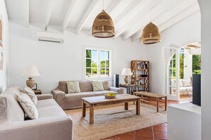 Ein geräumiges Wohnzimmer mit einer Couch, einem Couchtisch und dekorativen Korbtreleuchtern.