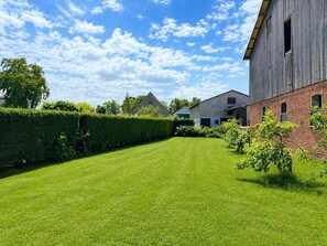 A well-maintained grassy area with a wooden building and a brick structure in the background. - Jagels-Hammann farm, fitters' apartment, An der Schule 6, 27607 Geestland (Geestland)