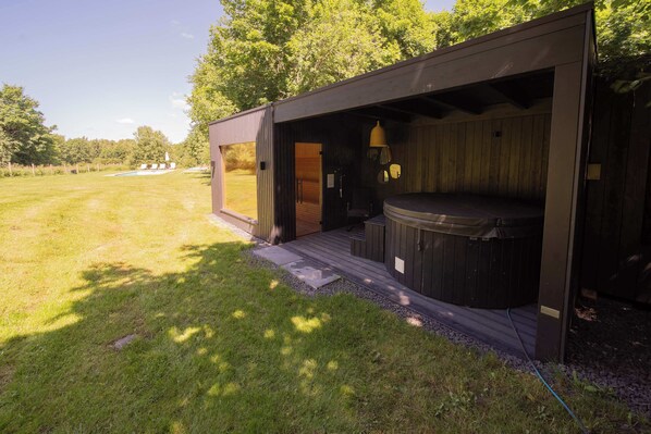 A hot tub area with a wooden deck and a covered seating area.