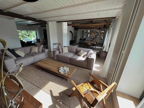 A spacious living area with a large sofa, a coffee table, and a dining area in the background.