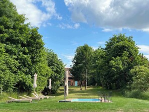 Un patio trasero con piscina, sillas de descanso y un área de estar cubierta.
