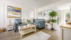 Ein modernes Wohnzimmer mit einem grauen Sofa, einem Couchtisch, einer Lampe und einem großen abstrakten Gemälde.