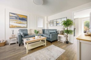 Ein modernes Wohnzimmer mit einem grauen Sofa, einem Couchtisch, einer Lampe und einem großen abstrakten Gemälde.