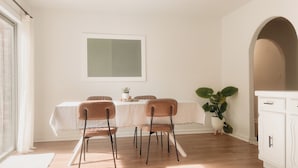 Un coin repas comprenant une table, des chaises, une plante en pot et un meuble blanc.