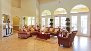 A spacious lobby with high ceilings, large arched windows, and a variety of seating arrangements including sofas and chairs. - Lakefront 4BR Disney Home with Pool & Game Room (Kissimmee)