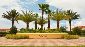 A landscaped area with palm trees and a sign reading 'Bella Vida.' - Lakefront 4BR Disney Home with Pool & Game Room (Kissimmee)