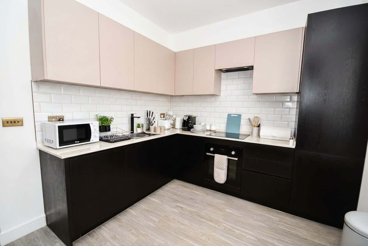 A modern kitchen with black and white cabinetry, a microwave, and a dishwasher.