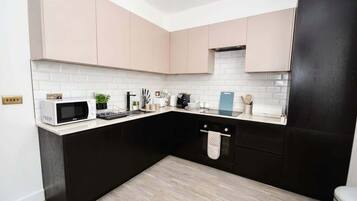 A modern kitchen with black and white cabinetry, a microwave, and a dishwasher.