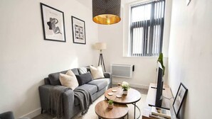 Ein modernes Wohnzimmer mit einem grauen Sofa, einem runden Couchtisch und einer TV-Konsole.