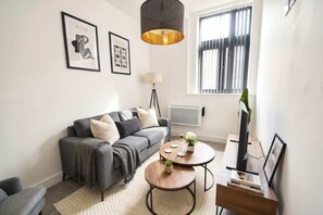 A modern living room with a grey sofa, a round coffee table, and a TV stand. - Cozy Central Wakefield 1BR Apt (Wakefield)