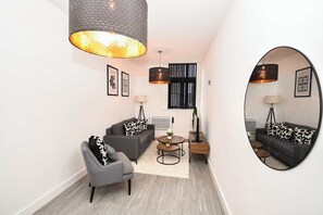 A modern living room with a sofa, armchair, coffee table, and a large mirror. - Spacious 1 Bedroom Apartment in Central Wakefield (Wakefield)