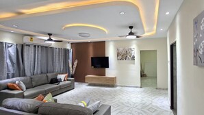 A modern living room with a sofa, TV, ceiling fan, and artwork.