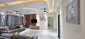 A modern living room with a sofa, TV, ceiling fan, and artwork. - beautifully updated, centrally located offering air-conditioning in every room (Greater Accra Region)