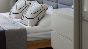 Una camera da letto con un letto, un comodino, una lampada e una finestra con tende.